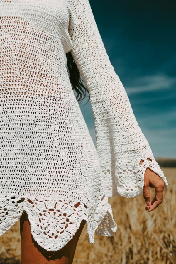 White crochet fabric and scalloped edges against a blue sky.